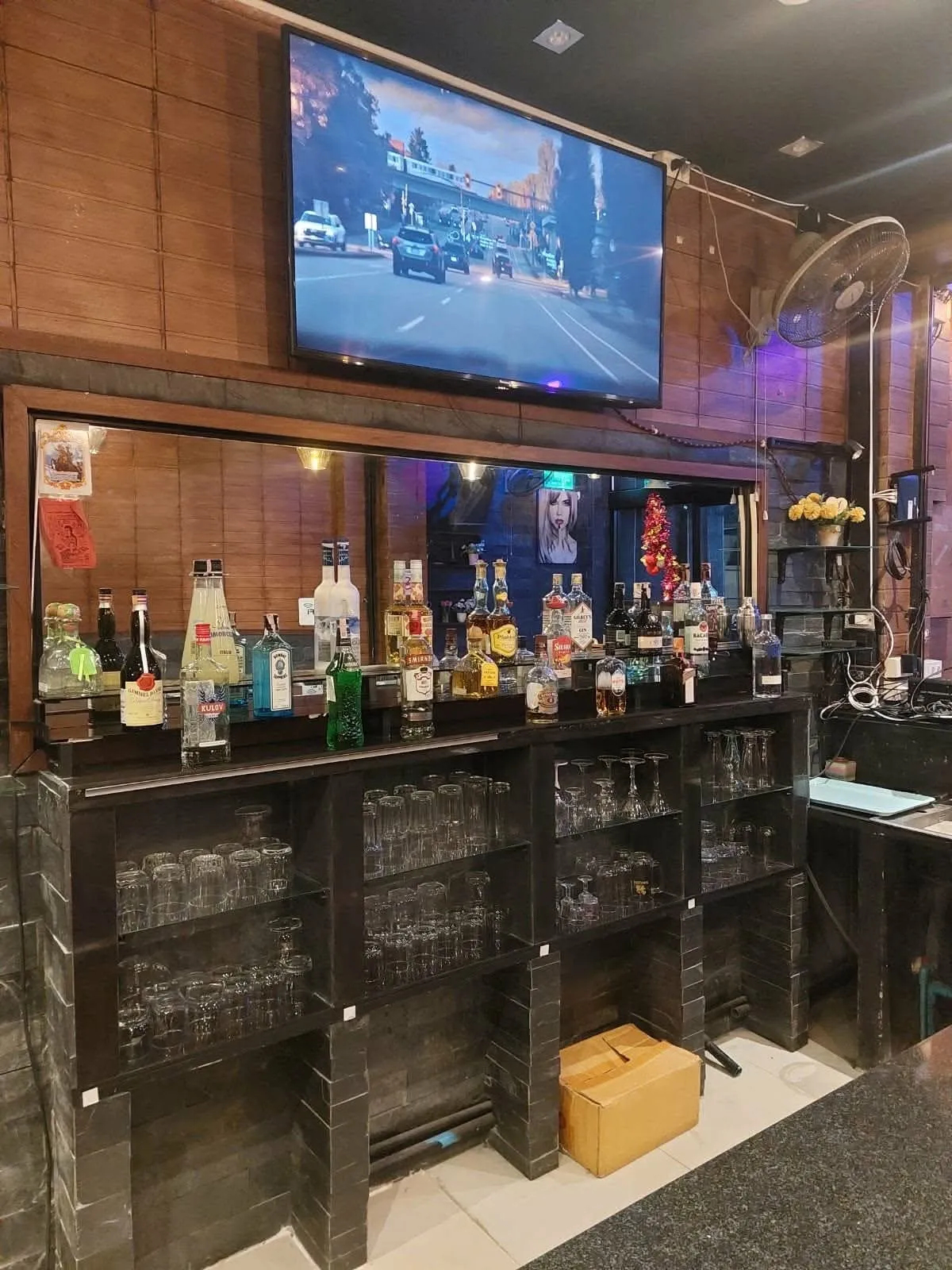 The back bar in the evening, bottles and glassware lit along the shelves