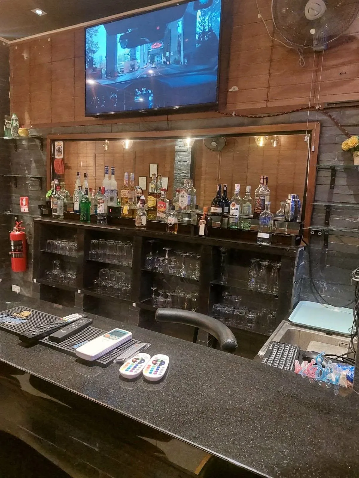 The bar counter with the spirits shelf and screen behind it