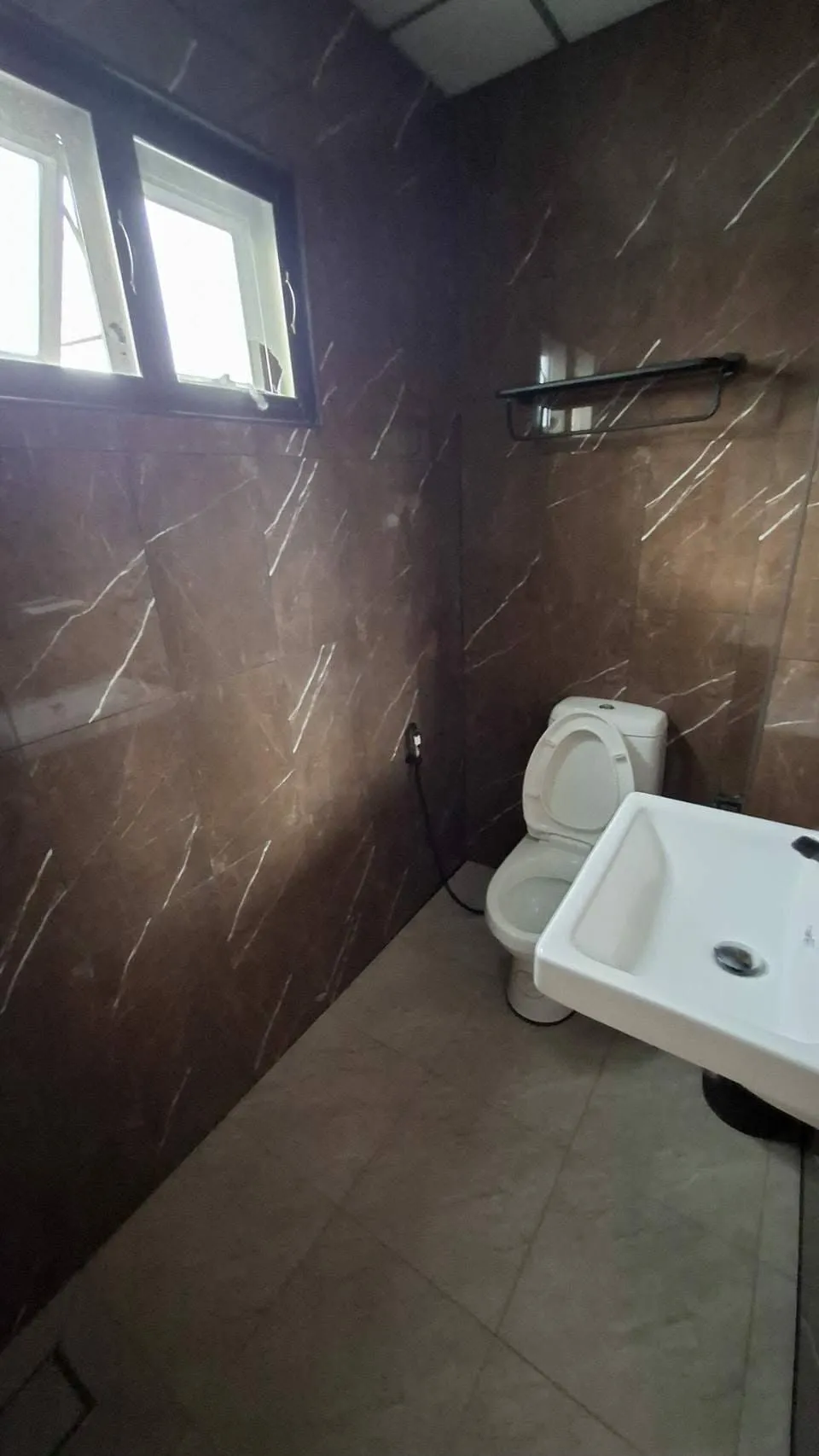 Ensuite bathroom with a toilet, sink and marble-tiled walls