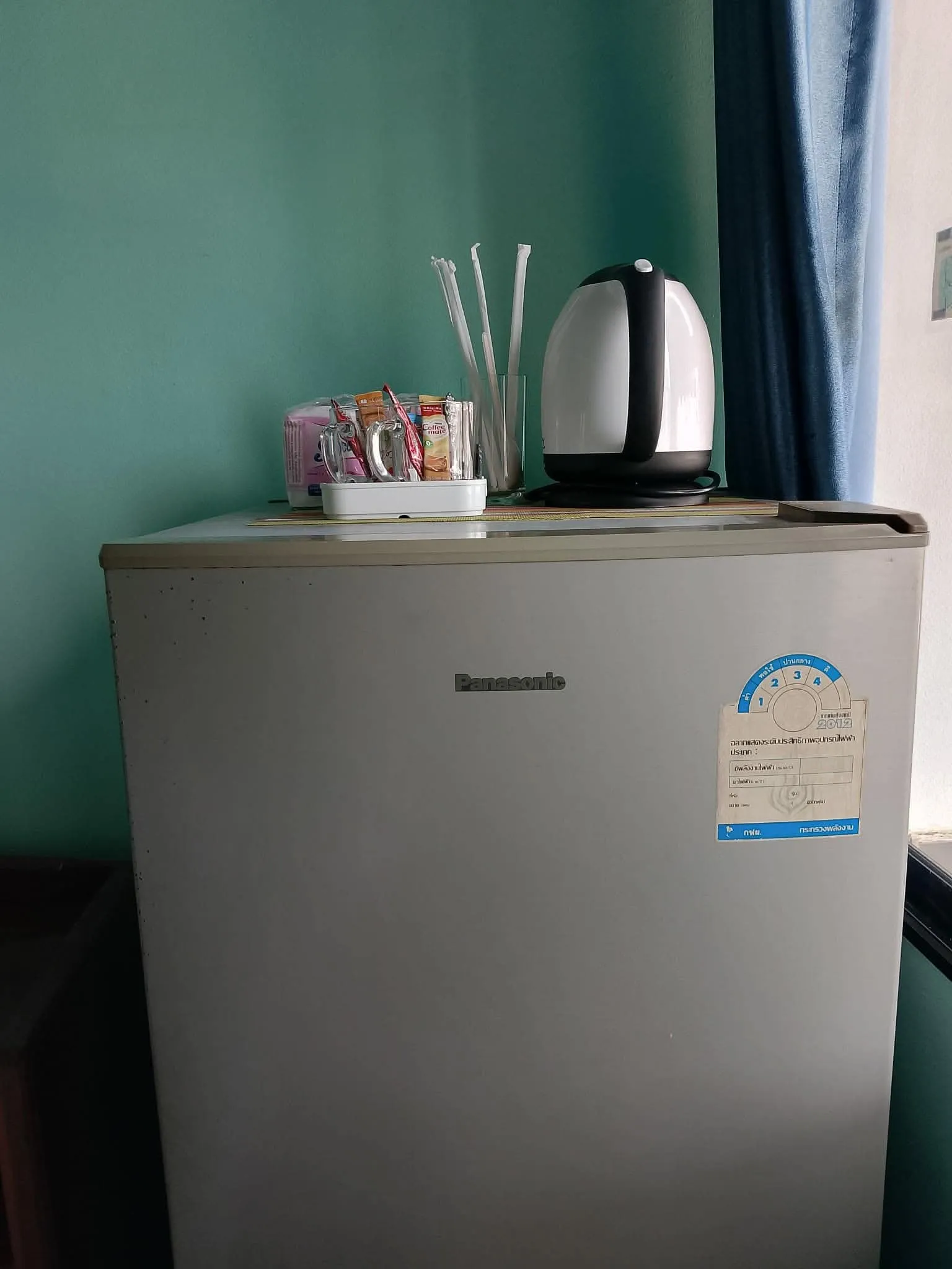 In-room fridge with a kettle and complimentary drinks on top