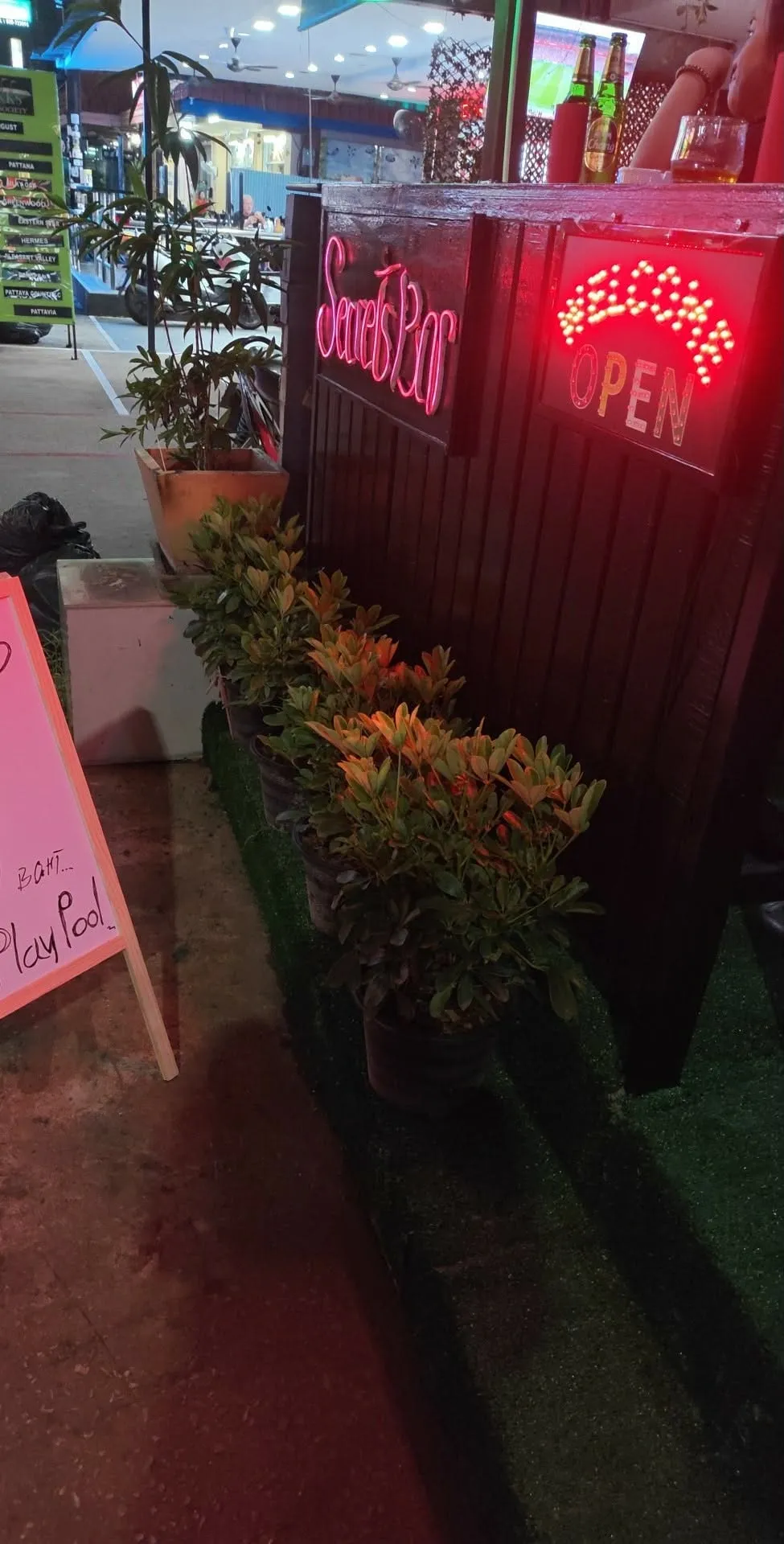 The neon Secrets Bar welcome sign beside the entrance