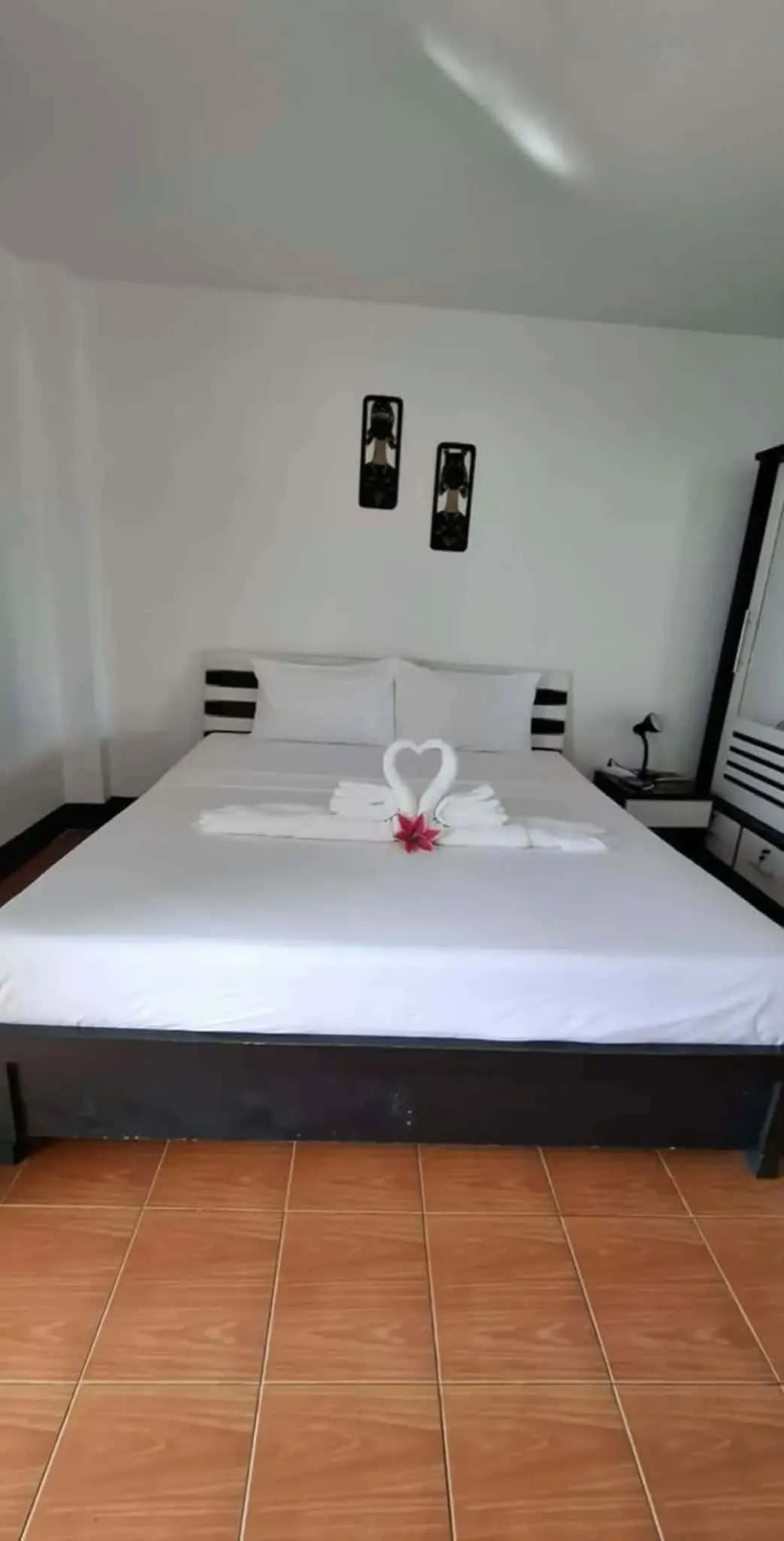 Made-up double bed with a flower laid on the towels and wall prints above
