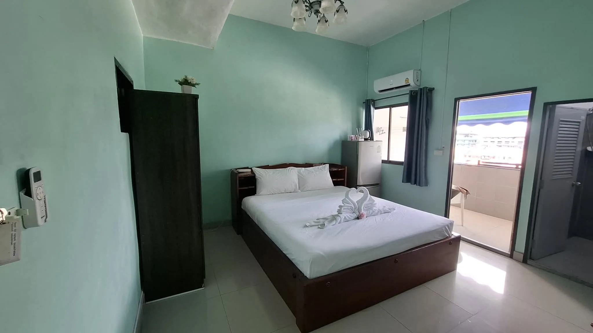 Deluxe King Room. Bright room with mint-green walls, a double bed and a door to the balcony
