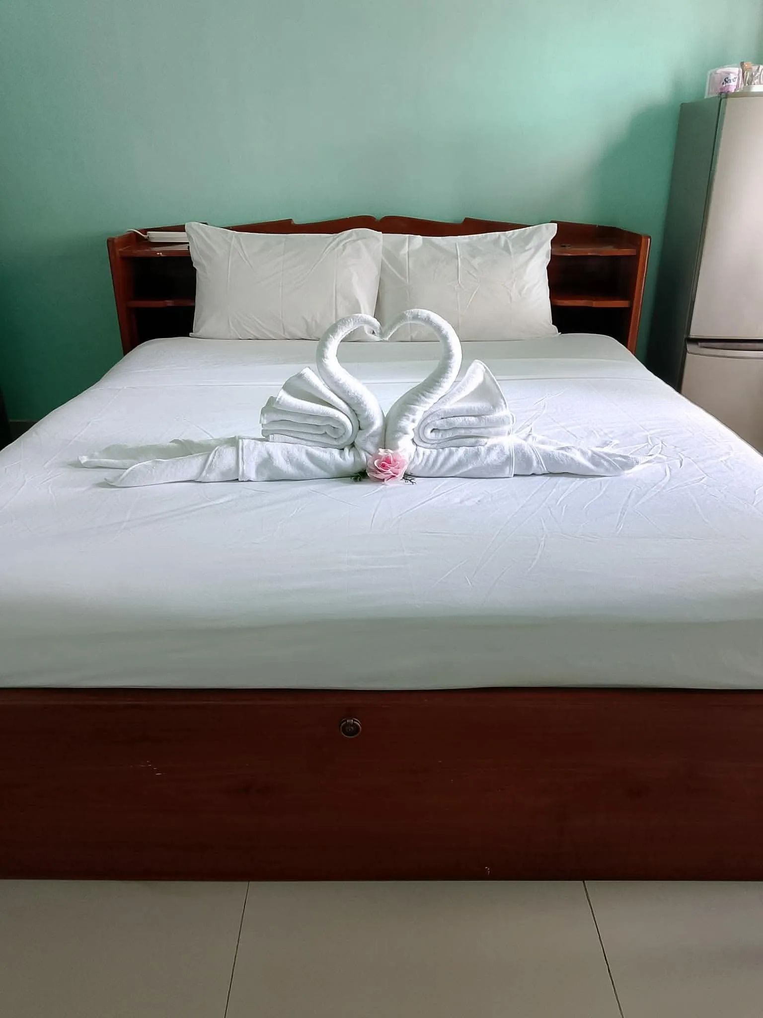 Wide double bed with a wooden headboard against a mint-green wall