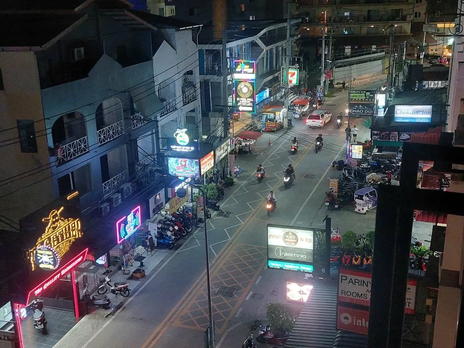 The soi at night, neon signage and motorbikes along the street